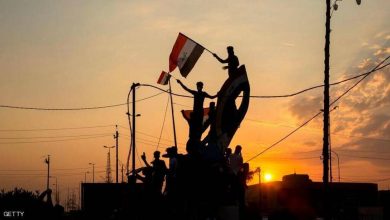 متظاهرون يرفعون علم العراق