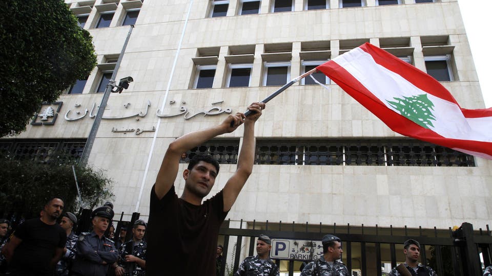 متظاهر لبناني يلوح بعلم بلاده أمام مصرف لبنان المركزي