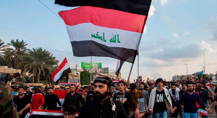 متظاهرون عراقيون يرفعون العلم