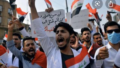 متظاهرون عراقيون يرفعون العلم العراقي